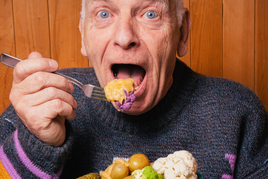 Man eating a plate of vegetables covered in Vegan Raclette with a surprised and excited expression